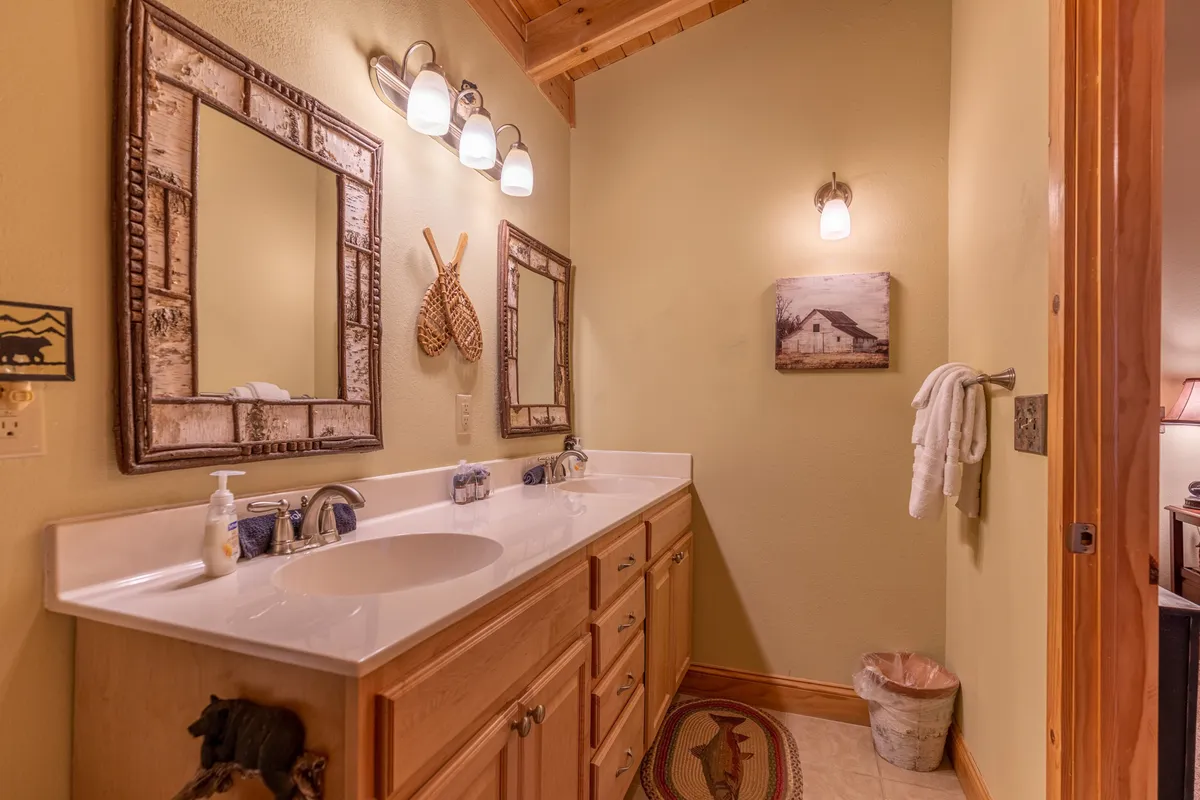 An inviting bathroom scene with a double sink vanity, framed mirrors, and decorative accents. Warm morning light creates a welcoming atmosphere, suggesting convenience and comfort for guests.