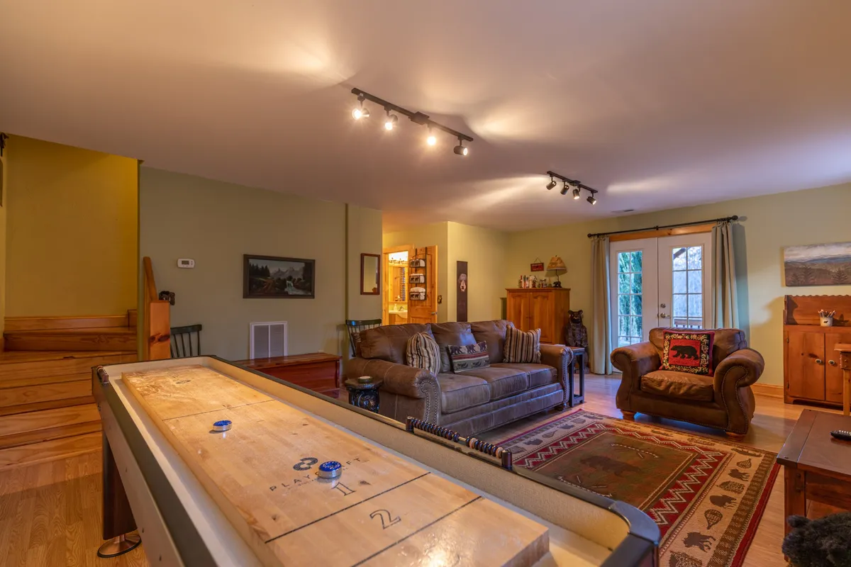 This interior image features a cozy shuffleboard table surrounded by comfortable seating and wooden furniture, suggesting a lively and playful atmosphere perfect for family tournaments and group fun after a day of local exploration.